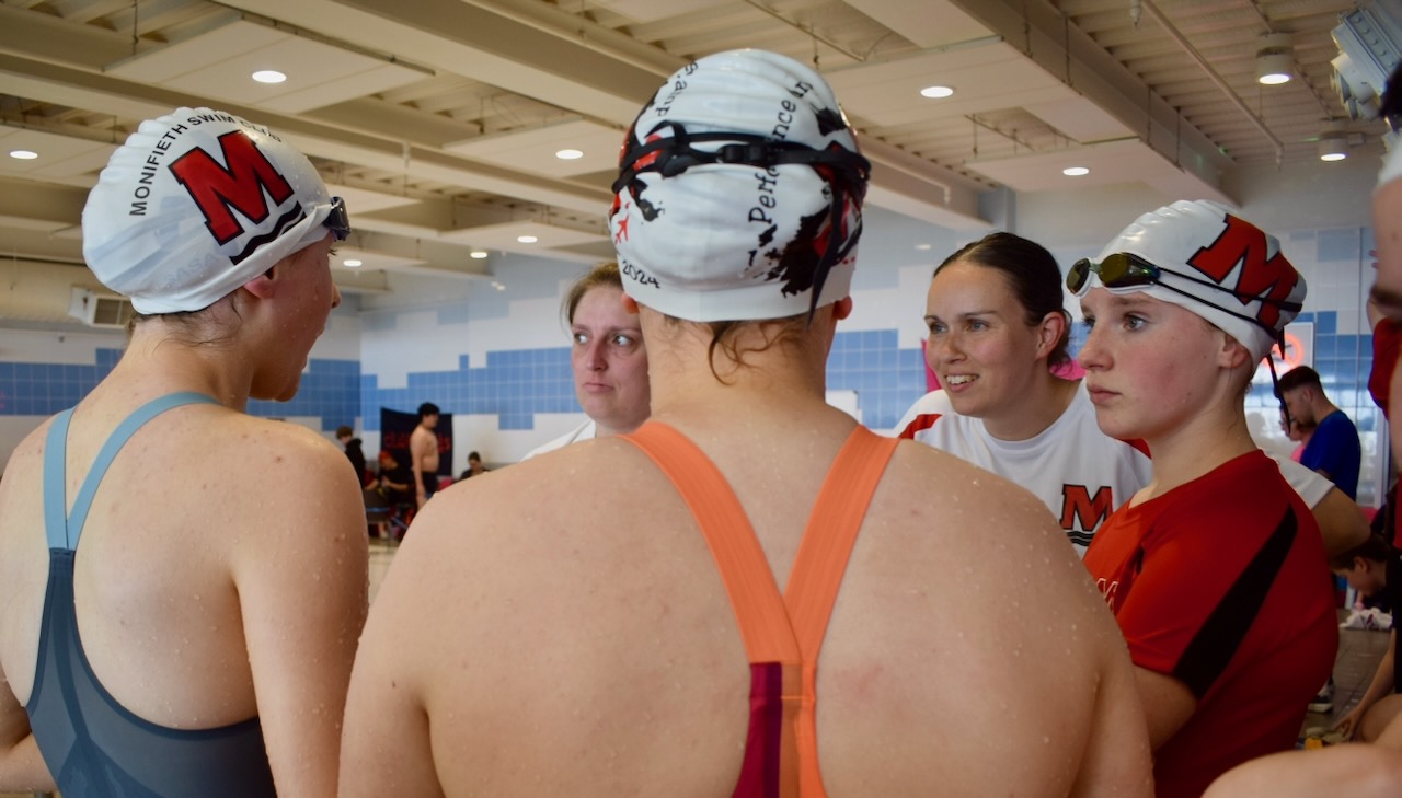Monifieth swimmers and coaches talking together at poolside